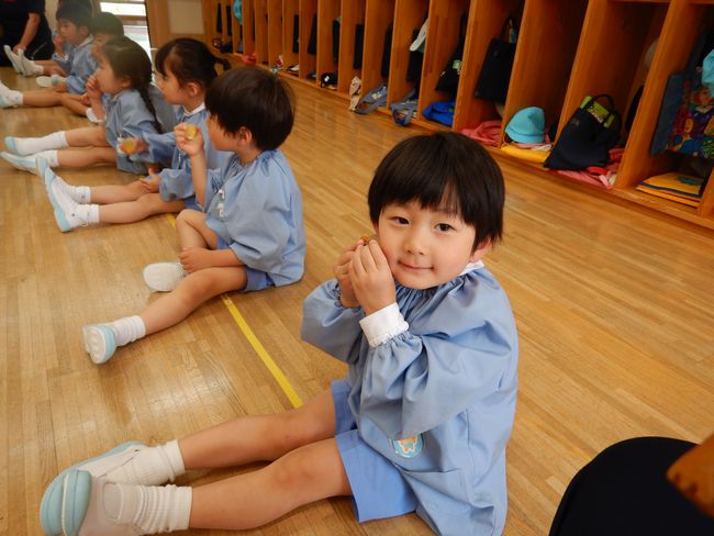 冷たいゼリーを頬につける年少児