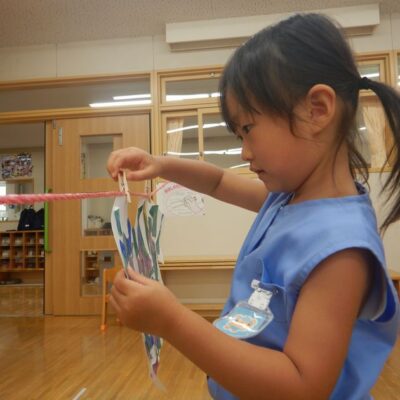 手指を使って洗濯ばさみを付ける園児