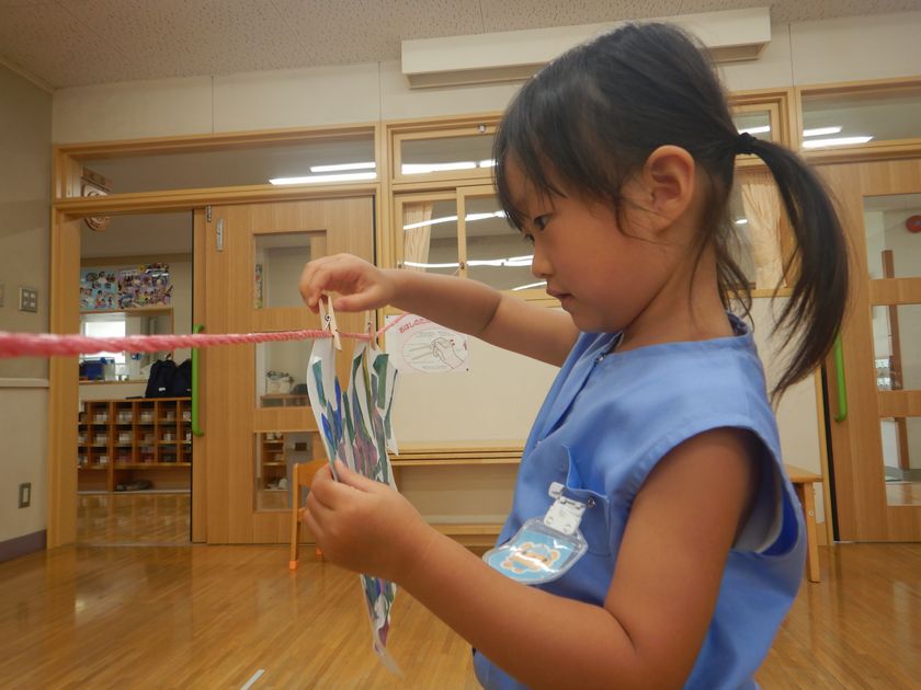 手指を使って洗濯ばさみを付ける園児